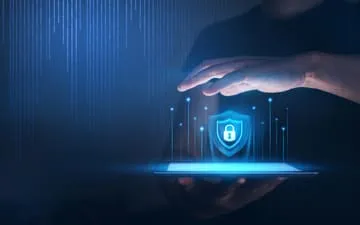 O que é Segurança da Informação nas empresas? Na imagem, mão sobre o símbolo de um cadeado em alusão à importância de contratar o seguro cyber para empresas.